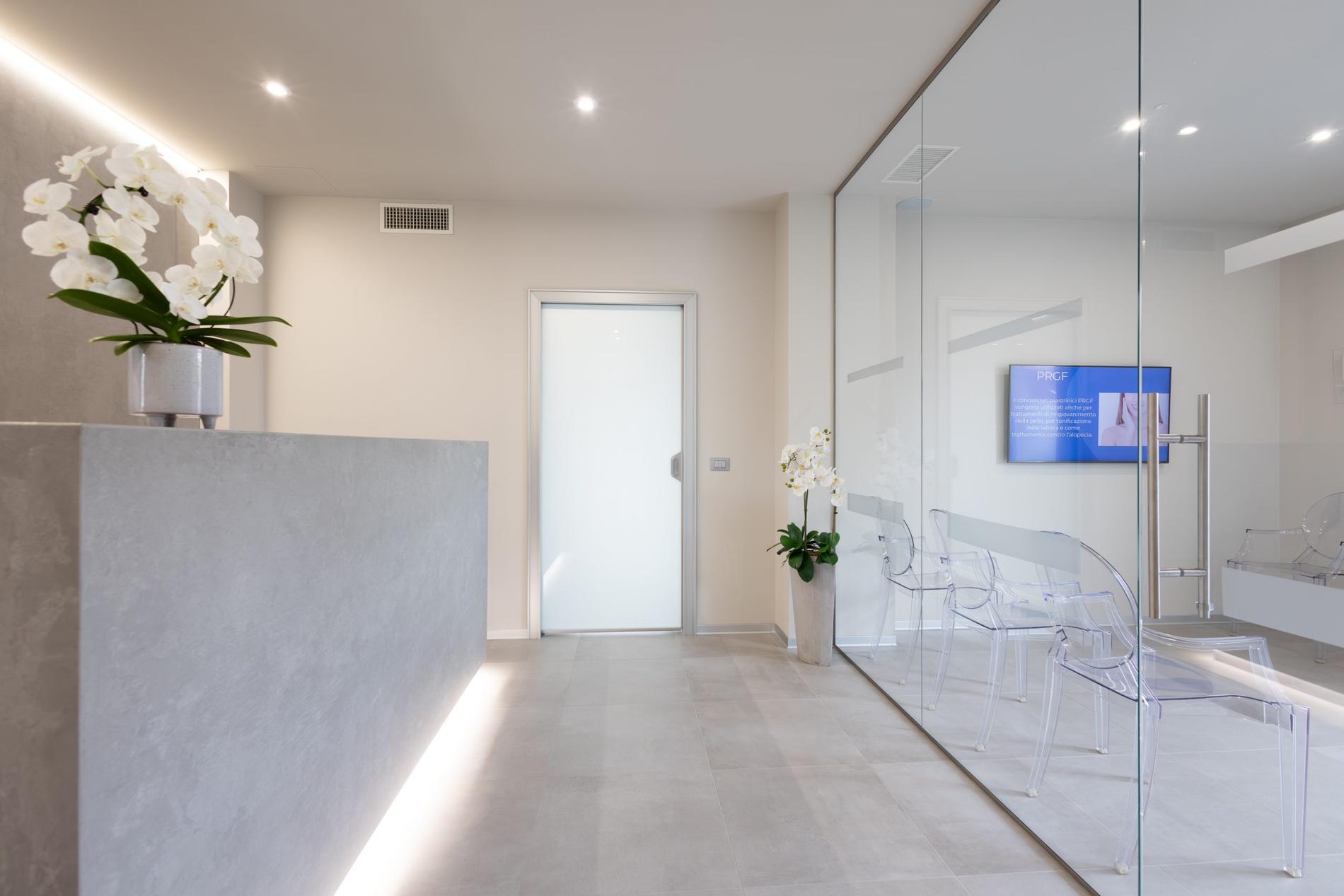 La reception dello studio: bancone chiaro, orchidee e vetrate sul corridoio